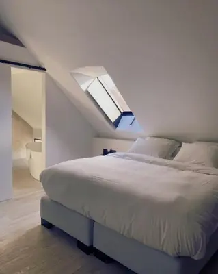 a white bedroom with a bed with a skylight at B&B Amelhof in Meise