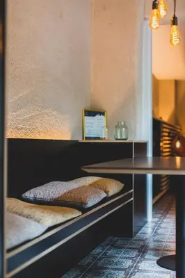 a shelf with two cushions on it next to a table at The Hide in Ghent
