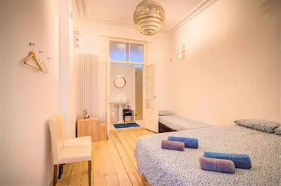 a bedroom with two beds and a chair and a window at The Greenplace Lodge. Apartment in Heart of Antwerp. in Antwerp