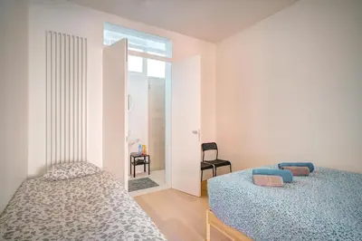a bedroom with two beds and a chair at The Greenplace Lodge. Apartment in Heart of Antwerp. in Antwerp