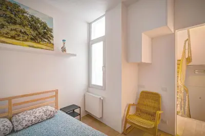 a bedroom with a bed and a chair and a window at The Greenplace Lodge. Apartment in Heart of Antwerp. in Antwerp