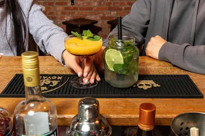 two people sitting at a table with two cocktails at MEININGER Hotels Bruxelles City Center in Brussels