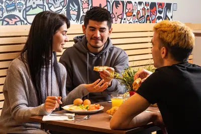 a group of people sitting at a table eating food at MEININGER Hotels Bruxelles City Center in Brussels