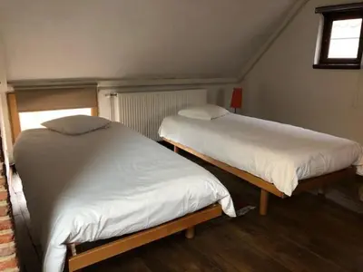 two twin beds in a room with a window at Trommelhoeve Farm Lofts in Boechout