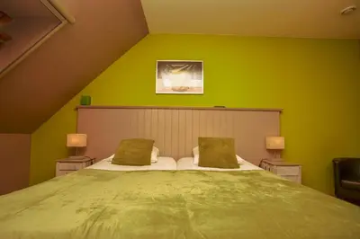 a bedroom with a large bed with green walls at B&B Fruithof Tack in Sint-Gillis-Waas