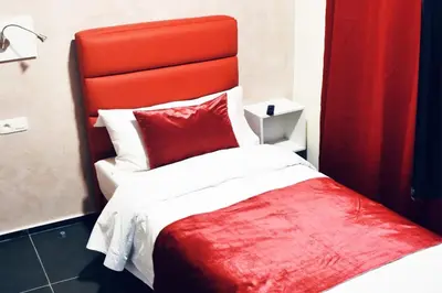 a red and white bed with a red head board at Hôtel onyx expo in Brussels