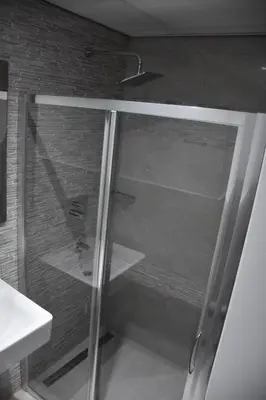 a glass shower door in a bathroom next to a sink at Hôtel onyx expo in Brussels