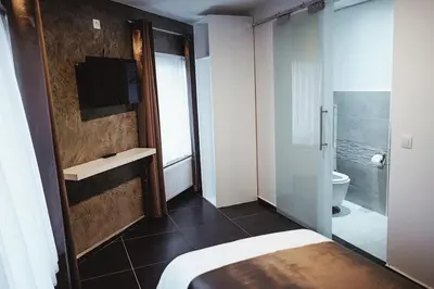 a bedroom with a bathroom with a toilet and a television at Hôtel onyx expo in Brussels