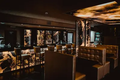 a restaurant with a bar with leather chairs and a ceiling at Hôtel onyx expo in Brussels