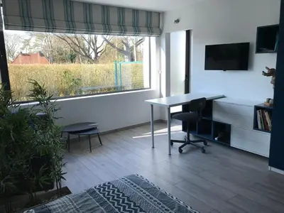 a living room with a desk and a large window at Au Calme in Sint-Genesius-Rode