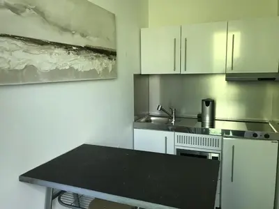 a kitchen with white cabinets and a black counter top at Au Calme in Sint-Genesius-Rode