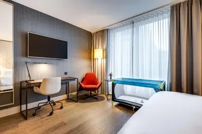 a hotel room with a bed and a desk and a television at NH Collection Antwerp Centre in Antwerp