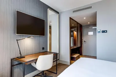 a bedroom with a desk and a tv on a wall at NH Collection Antwerp Centre in Antwerp