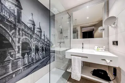 a bathroom with a sink and a glass wall at NH Collection Antwerp Centre in Antwerp
