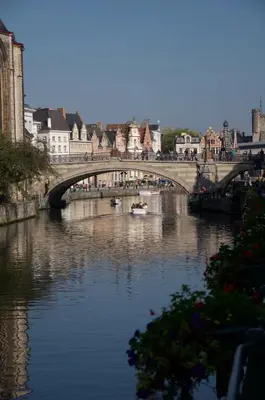 a bridge over a river with boats in the water at Artist's Loft & Garden in Ghent