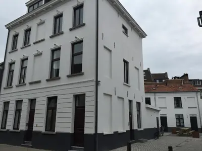 a white building with black windows on a street at Artist's Loft & Garden in Ghent