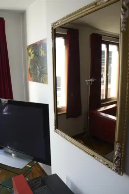 a desk with a computer and a mirror on a wall at Artist's Loft & Garden in Ghent