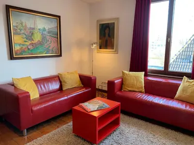 a living room with two red leather couches and a table at Artist's Loft & Garden in Ghent