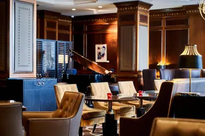 a restaurant with tables and chairs and a piano at Steigenberger Icon Wiltcher's in Brussels