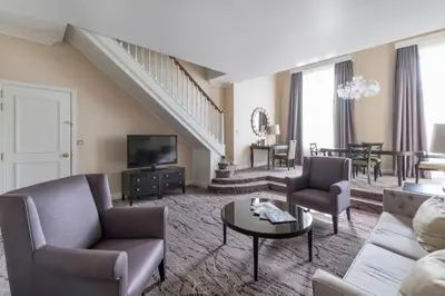 a living room with a couch and a tv at Steigenberger Icon Wiltcher's in Brussels