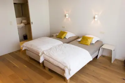 two beds in a room with white walls and yellow pillows at Mon Dieu in Scherpenheuvel-Zichem