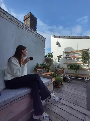 a woman sitting on a bench drinking a cup of coffee at Violet Suites in Ghent