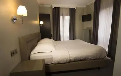 a bedroom with a white bed and a window at Hotel Chantecler in Brussels