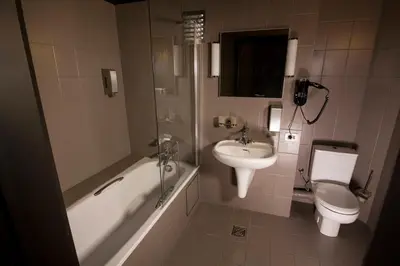 a bathroom with a tub and a toilet and a sink at Hotel Chantecler in Brussels