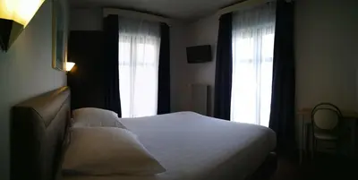 a bedroom with a white bed and two windows at Hotel Chantecler in Brussels