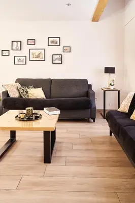 a living room with a black couch and a coffee table at Vakantiewoning De Gulden Sleutels in Kruibeke