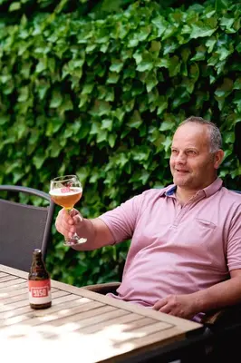 a man sitting at a table holding a glass of wine at Vakantiewoning De Gulden Sleutels in Kruibeke