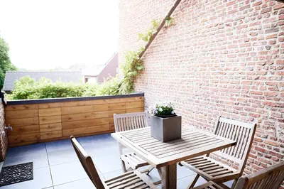 a patio with a table and chairs and a brick wall at Vakantiewoning De Gulden Sleutels in Kruibeke