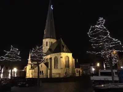 a church with a steeple and christmas trees at night at Vakantiewoning De Gulden Sleutels in Kruibeke