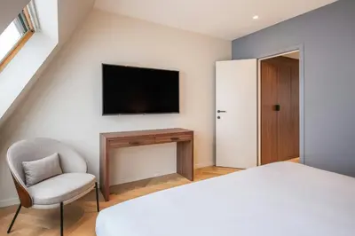 a bedroom with a bed and a chair and a television at Marriott Executive Apartments Brussels in Brussels