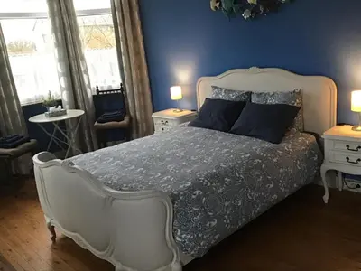 a bedroom with a white bed with blue walls and windows at Room Feliz in Zele