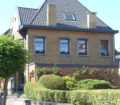 a brown brick house with windows and bushes at Room Feliz in Zele