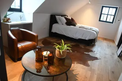 a living room with a table and a bed at Ask Lily in Westmeerbeek