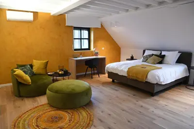 a bedroom with a bed and a chair and a table at Ask Lily in Westmeerbeek