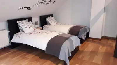 a bedroom with two beds and a wood floor at CEP MAISONNETTE in Brussels