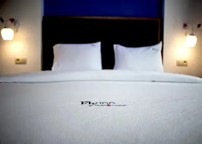 a bed with a white bedspread and two pillows at Fly inn Hotel Lounge & Nezzo Restaurant in Machelen