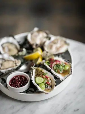a plate of oysters on a plate with sauce at august in Antwerp