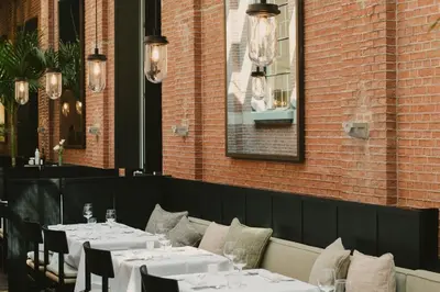 a restaurant with white tables and chairs and a brick wall at august in Antwerp