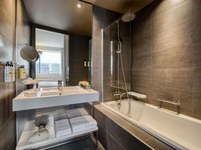 a bathroom with a tub and a sink and a bath tubermott at Pullman Brussels Centre Midi in Brussels