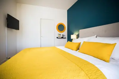a bedroom with a large bed with a yellow blanket at Chez Spoons B&B in Bossut-Gottechain