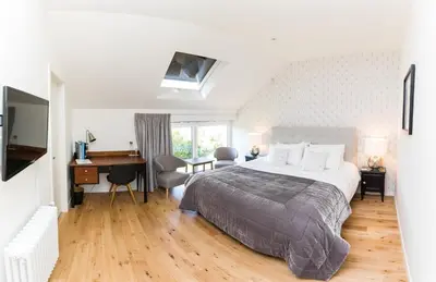 a bedroom with a large bed with a desk and a piano at Chez Spoons B&B in Bossut-Gottechain