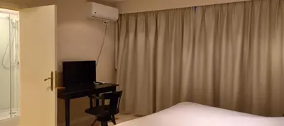 a bedroom with a bed and a desk with a computer at Hotel De Croone in Ninove