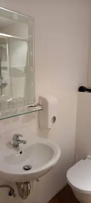 a white bathroom with a sink and a toilet at Hotel De Croone in Ninove