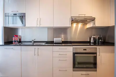a kitchen with white cabinets and a sink at Thon Residence Florence Aparthotel in Brussels
