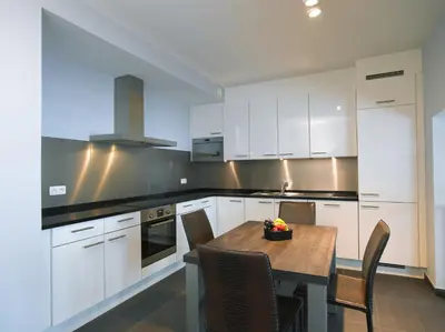 a kitchen with white cabinets and a table with chairs at Thon Residence Florence Aparthotel in Brussels