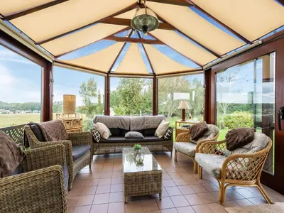 a screened in porch with furniture and windows at Charming Nieuwpoort Mill Retreat in Zottegem